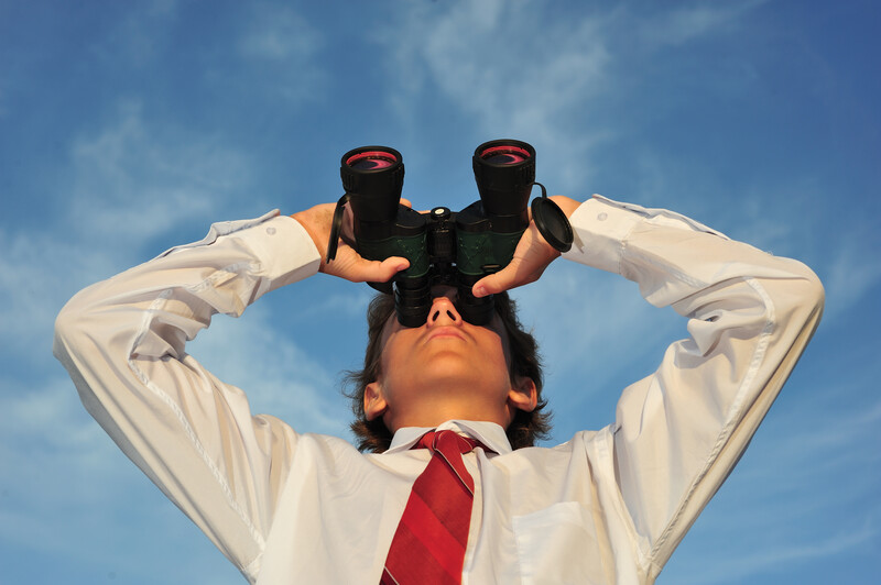 Young business man looking through binocular, low angle view_canstockphoto1666946 800X533